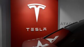 Автомобиль на фоне логотипа Tesla. Фото Milan Csizmadia / Unsplash