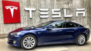 Электромобиль на фоне логотипа Tesla. Фото Tesla Fans Schweiz / Unsplash