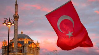 Флаг Турции на фоне мечети Ортакёй. Фото Meg Jerrard / Unsplash